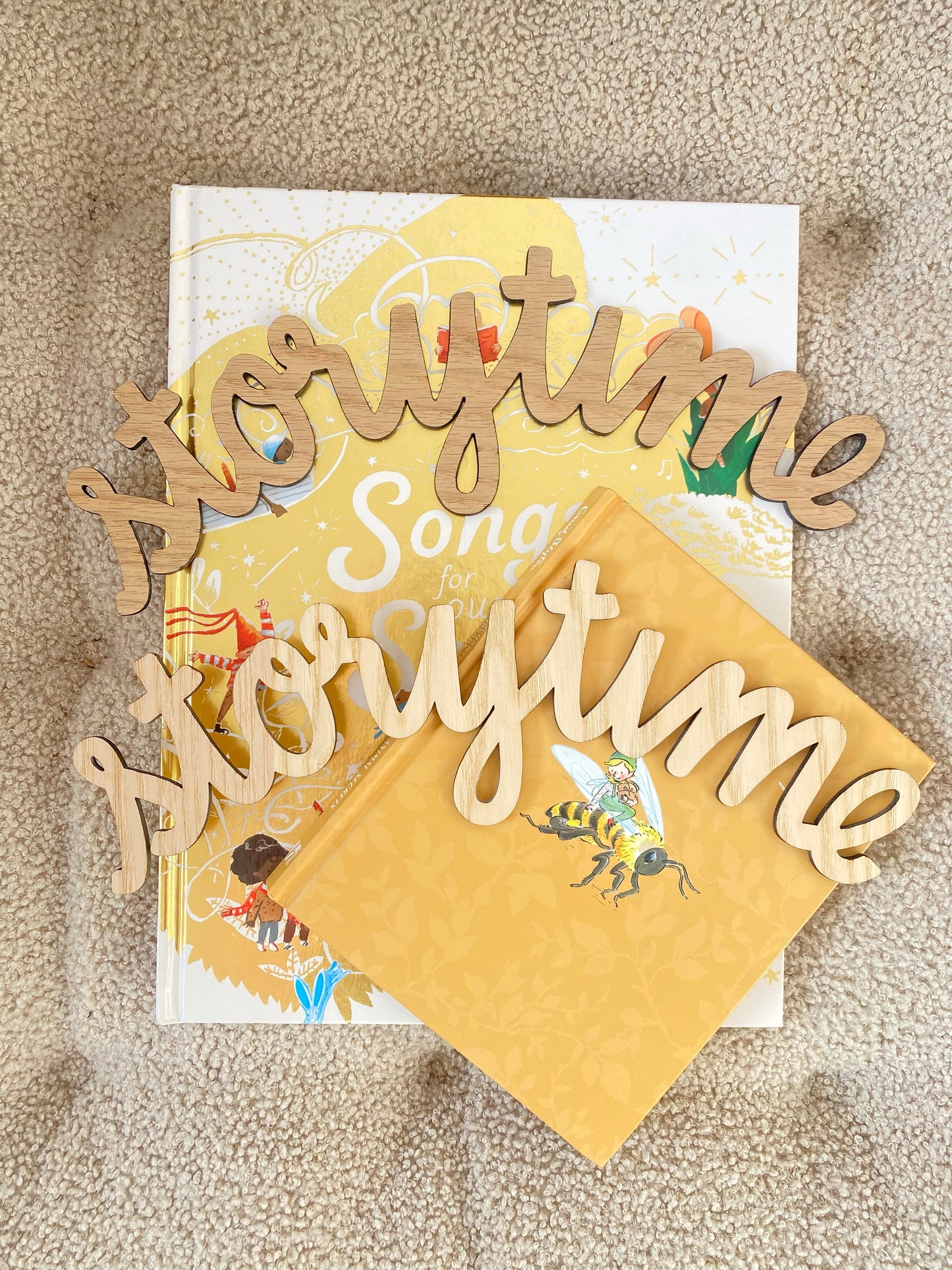 Wooden word decorations spelling 'Storytime' on a book and yellow card on a beige surface.