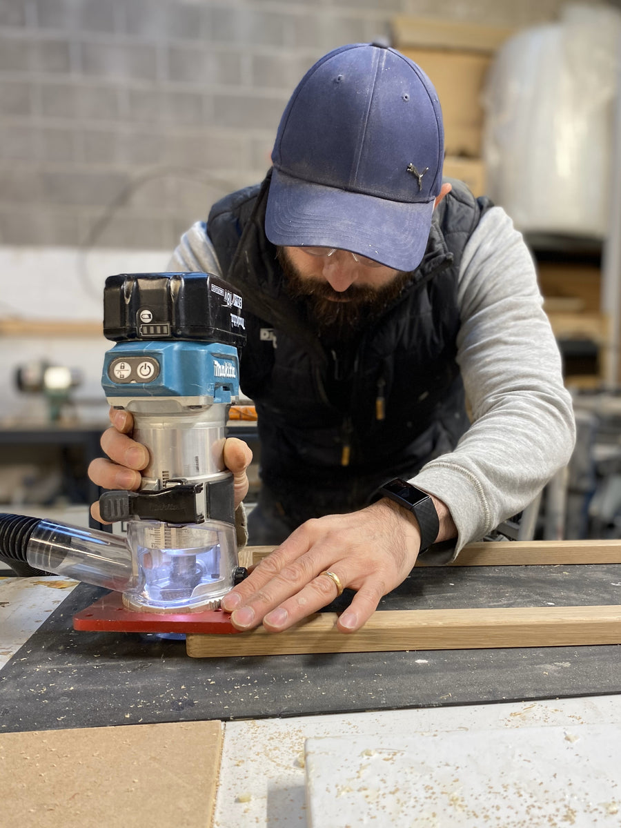 Luke shaping solid wood with a router in the Cardiff workshop