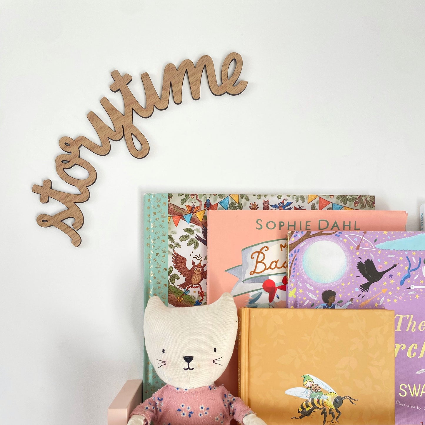 Children's books with a plush toy and 'storytime' sign on a white wall