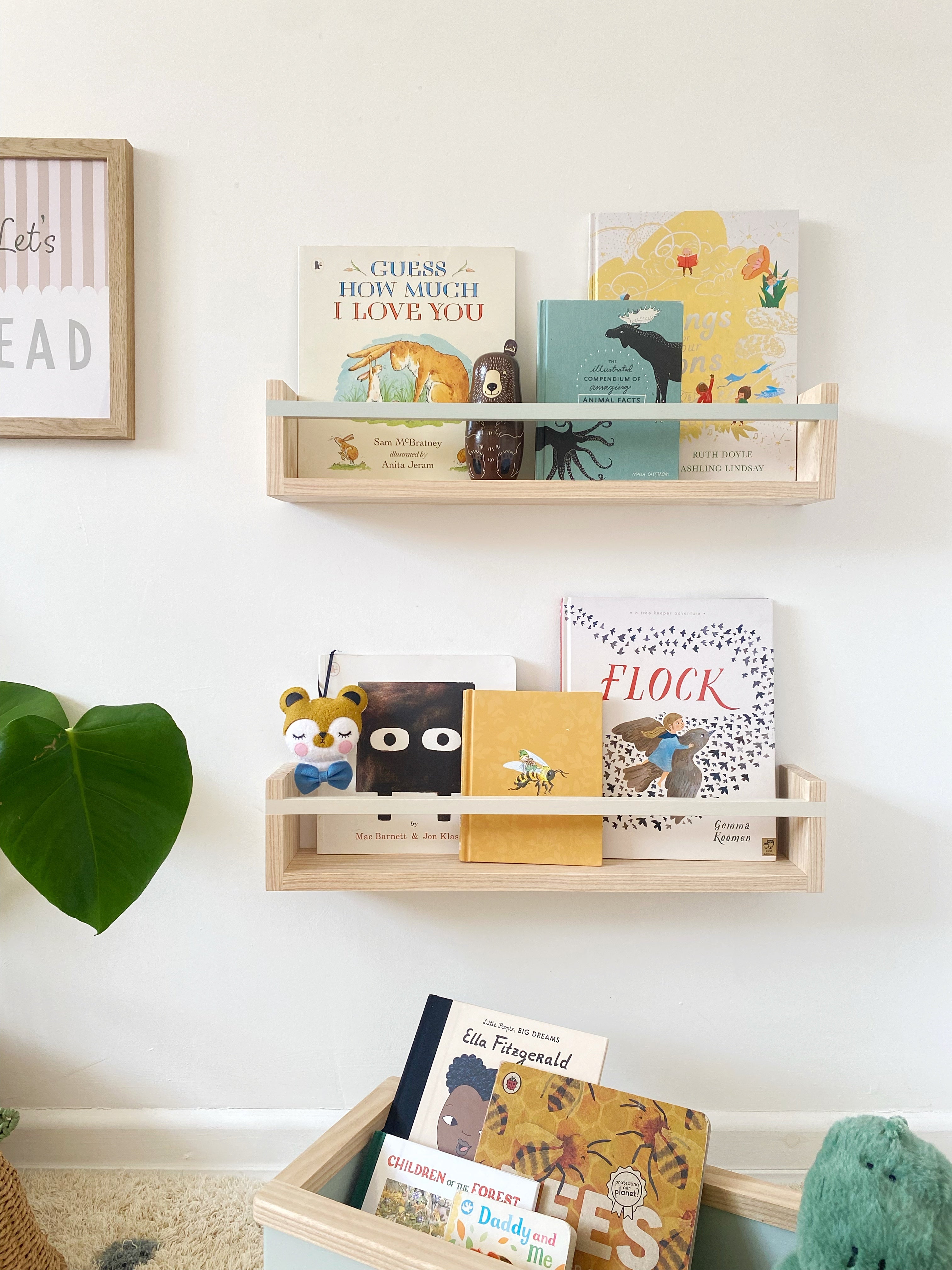 Wooden shelves with children's books and toys on a white wall.