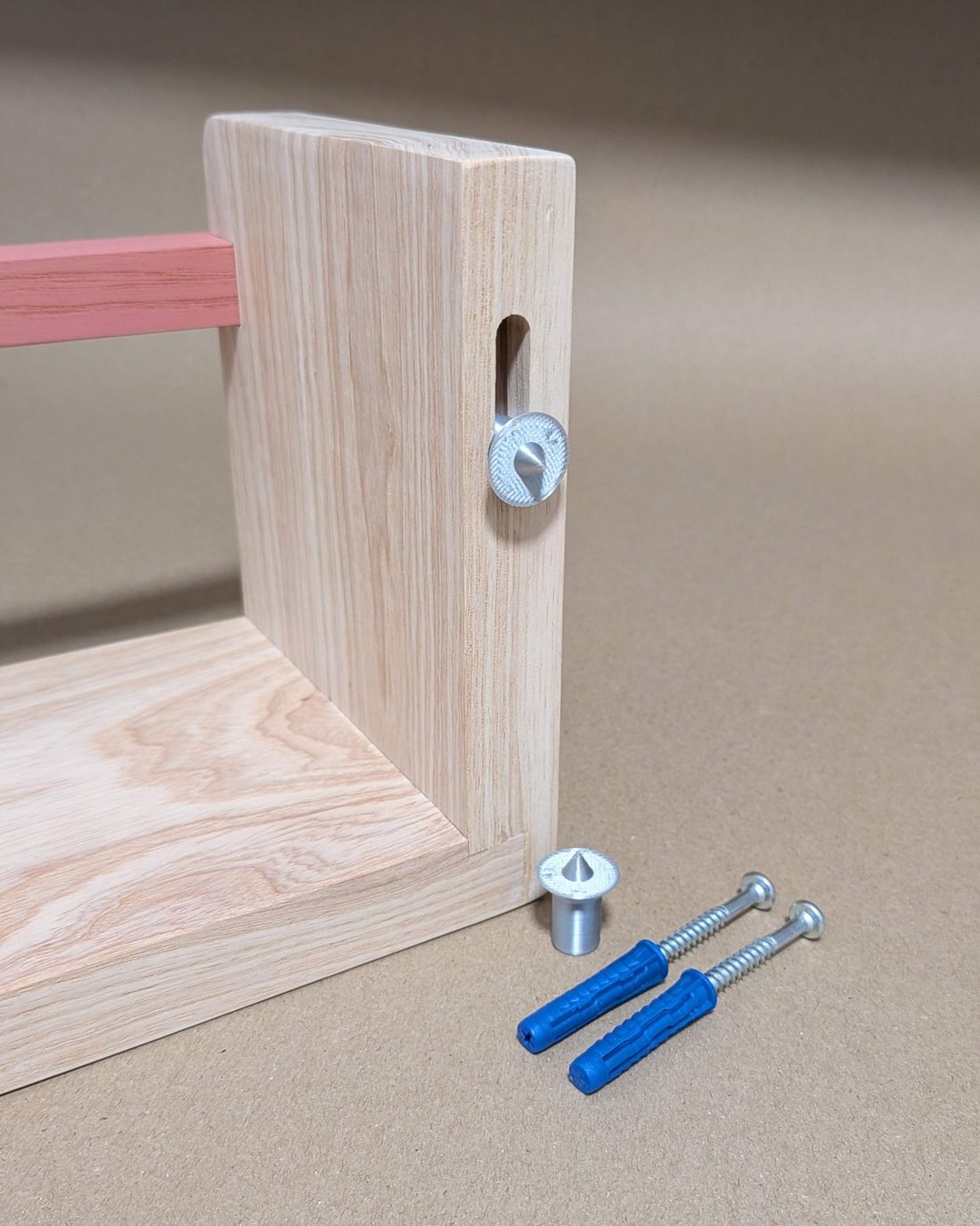Keyhole marker slotted into the back of a solid ash Story Shelf, with a spare marker, two screws and two wall plugs included in the box