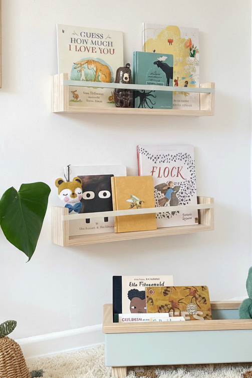 Wooden shelves with children's books and toys against a white wall.